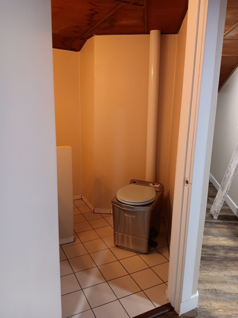 Incinerator toilet installation. Tile flooring. Half wall and bathroom framing.